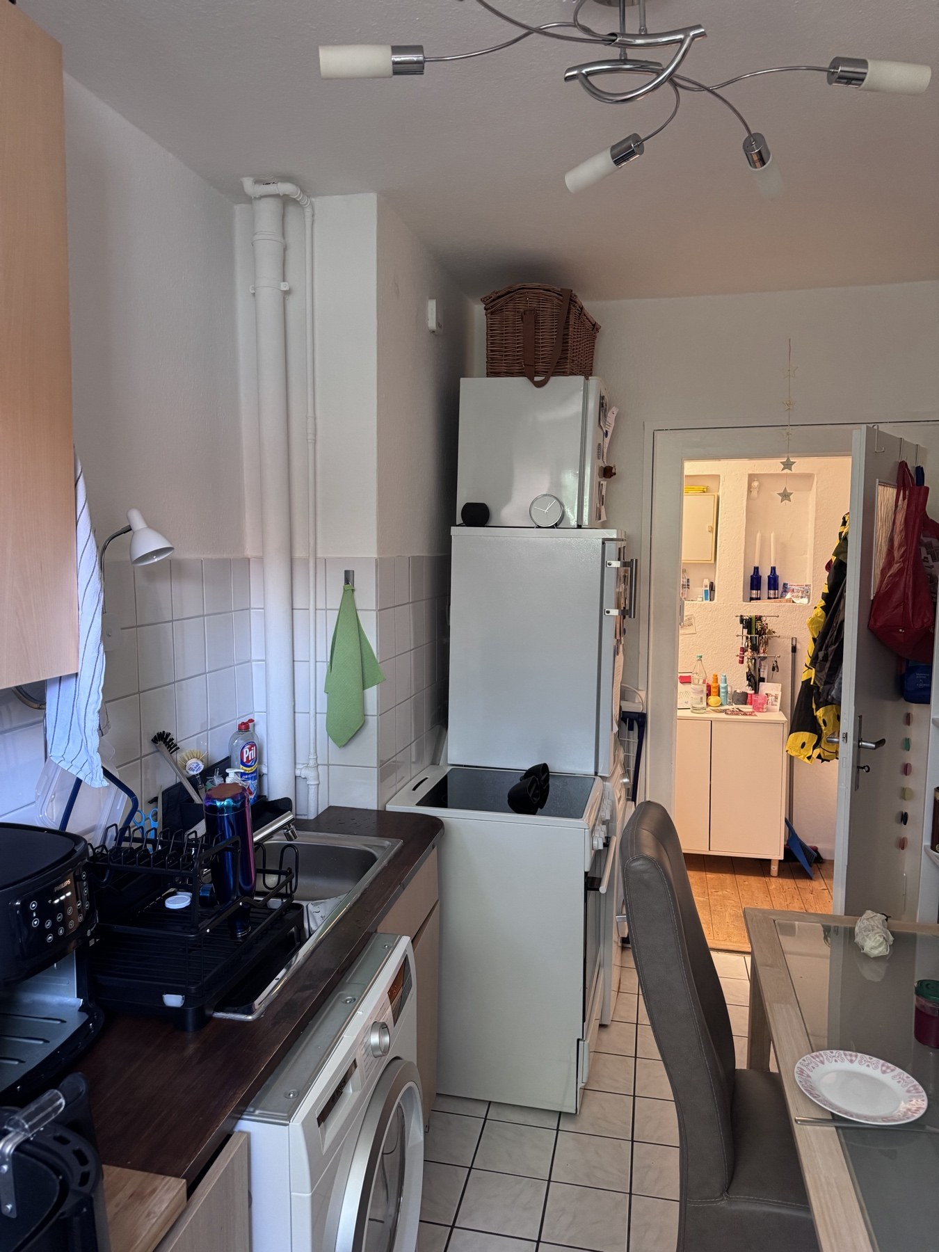 Küche aus zweiter Perspektive mit Kühlschrank, Herd und Waschmaschine
