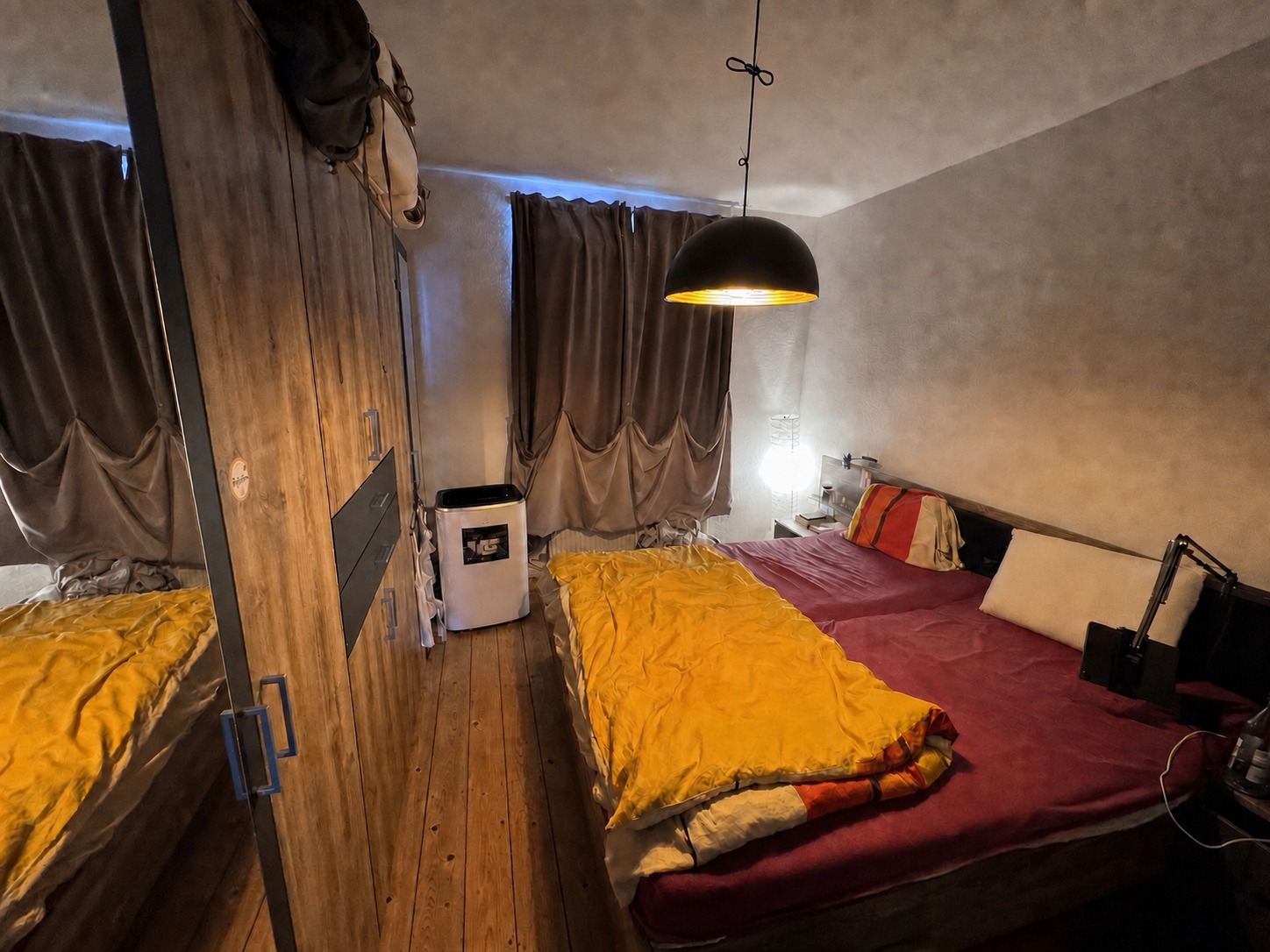 Schlafzimmer mit Doppelbett, Kleiderschrank und zwei Fenstern