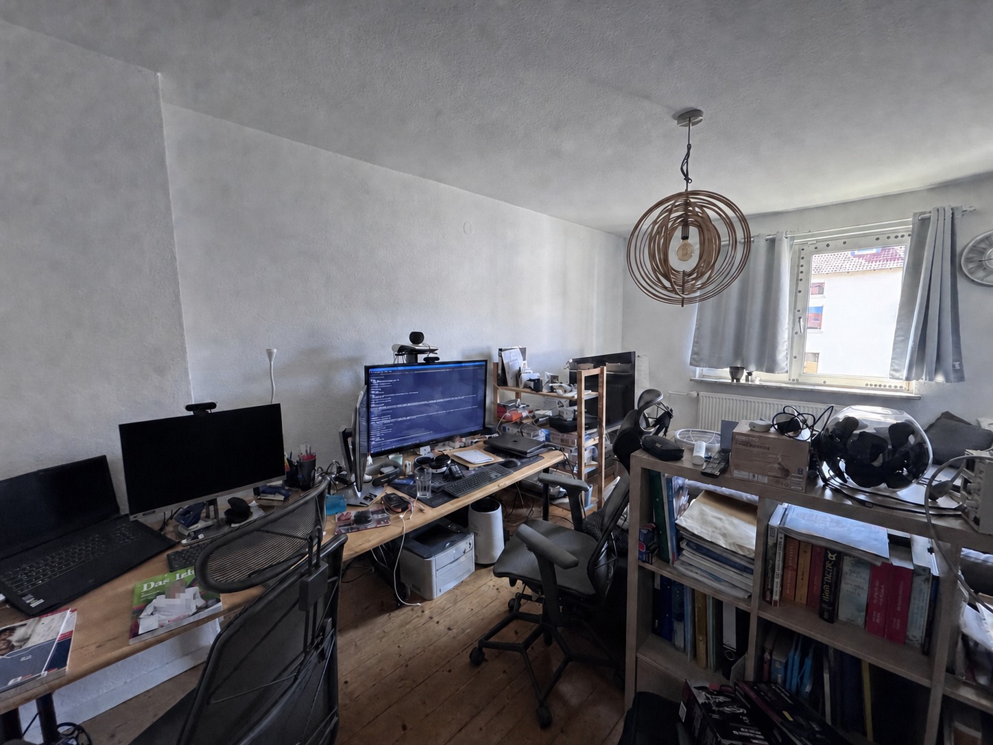 Wohn- und Arbeitszimmer mit mehreren Schreibtischen, Bürostühlen und Fenster
